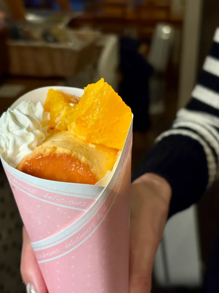 フルーツクレープカップ。ピンクのテイクアウトカップにイタリアンプリン、オレンジのロースト、ホイップクリーム入り、カフェ店内で撮影