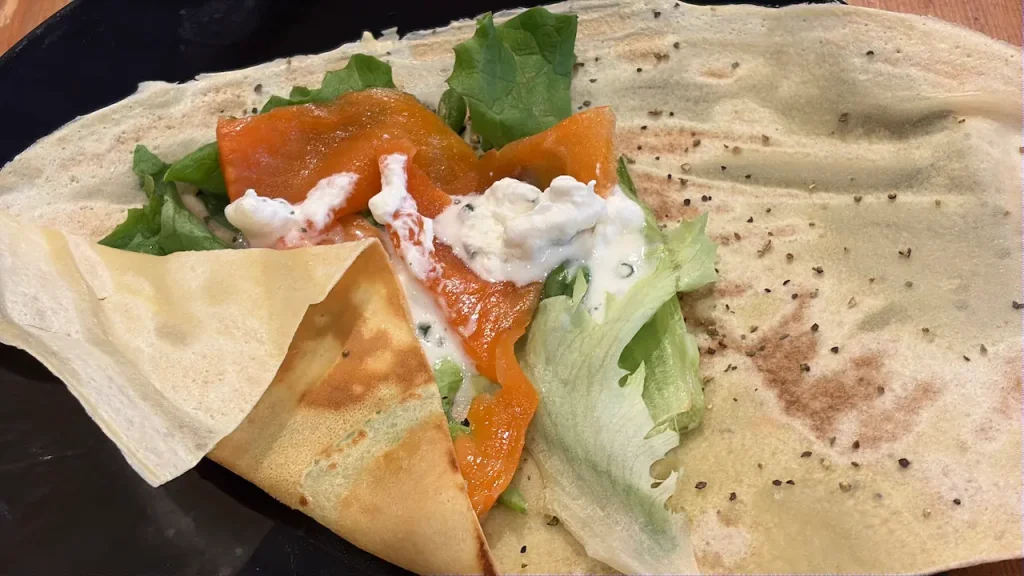 お食事用クレープ。スモークサーモン、レタス、クリームチーズ添え。黒胡椒トッピング、黒い皿に盛り付け