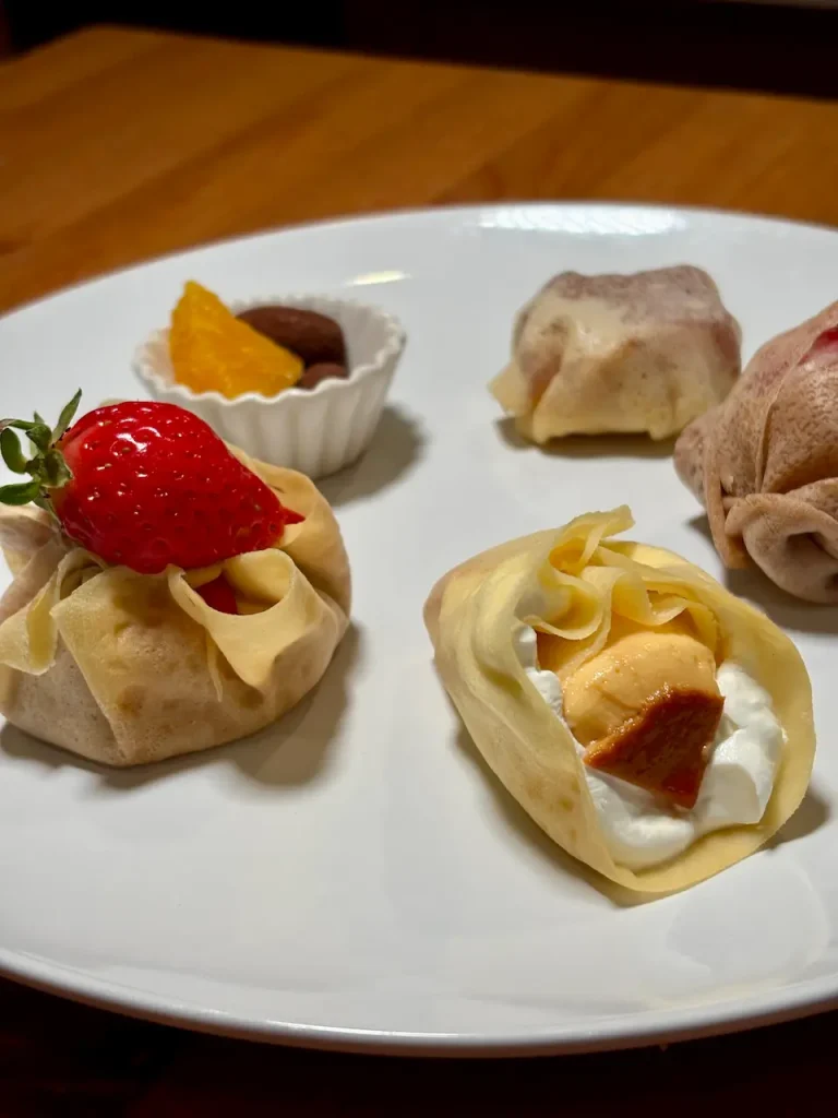「ミニクレープのデザートプレート。5種類のクレープ、いちごトッピング、生クリーム、焼きりんご、チョコレート、オレンジセグメント添え」